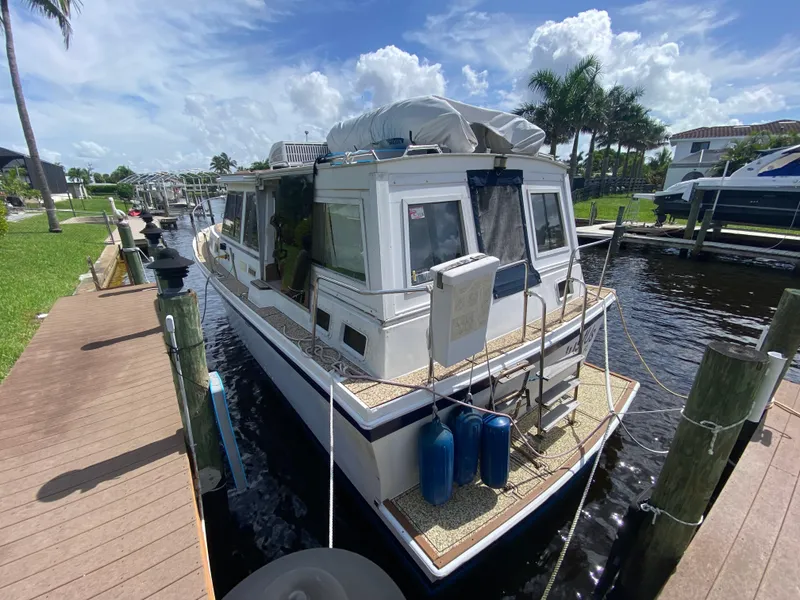 Slide: The Image of 1986 Albin 34 Family Cruiser docked by a wooden pier under a sunny sky. - 2