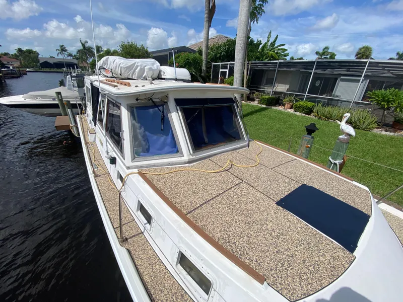 Slide: The Image of 1986 Albin 34 Family Cruiser docked by a lush, green waterfront. - 4