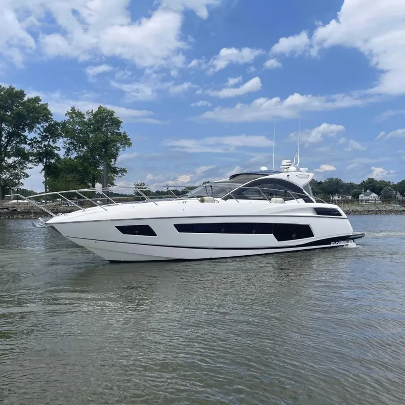 The Image of 2015 Sunseeker San Remo 48 yacht cruising on a calm river under a blue sky. - 0