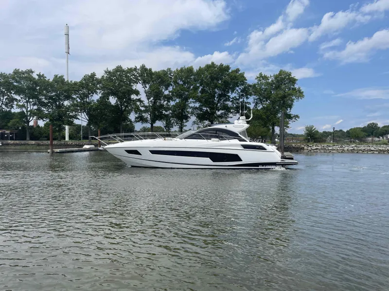 Slide: The Image of 2015 Sunseeker San Remo 48 yacht on calm water, surrounded by trees and blue sky. - 2