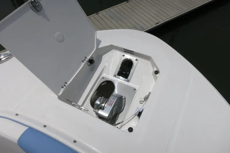Slide: The Image of 2025 Robalo R317 Dual Console anchor compartment with open hatch, dock in background. - 15