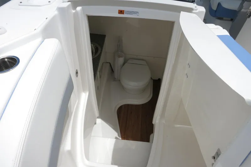Slide: The Image of 2025 Robalo R317 Dual Console boat interior with compact marine toilet. - 18