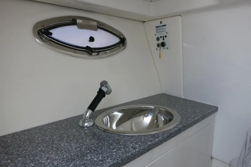 Slide: The Image of 2025 Robalo R317 Dual Console interior with sink and porthole window. - 19