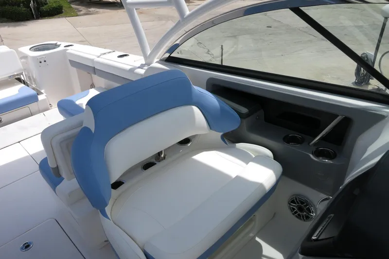 Slide: The Image of 2025 Robalo R317 Dual Console boat interior with blue and white seating and cup holders. - 25