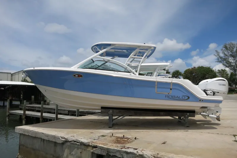 Slide: The Image of 2025 Robalo R317 Dual Console boat on a dock under a blue sky. - 3