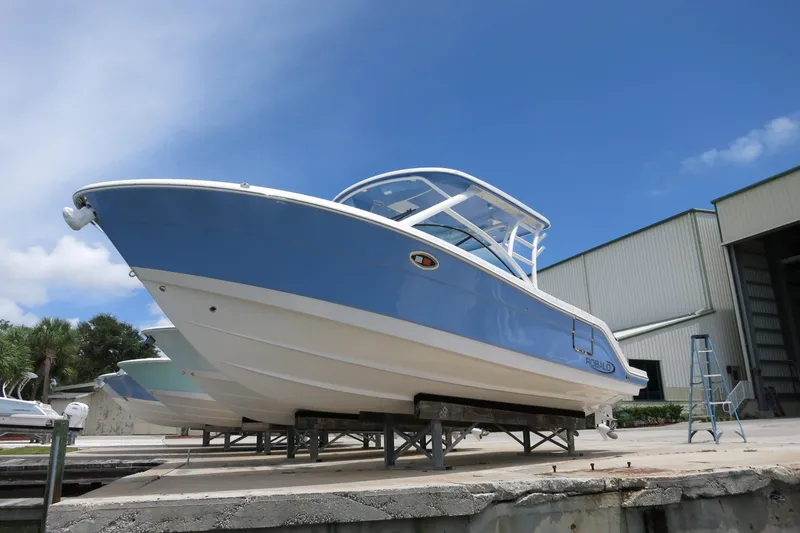 Slide: The Image of 2025 Robalo R317 Dual Console boat on display under clear blue sky. - 4