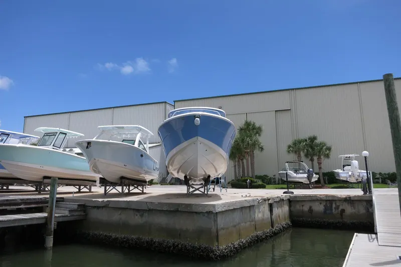 Slide: The Image of 2025 Robalo R317 Dual Console boats docked at marina under clear blue sky. - 5