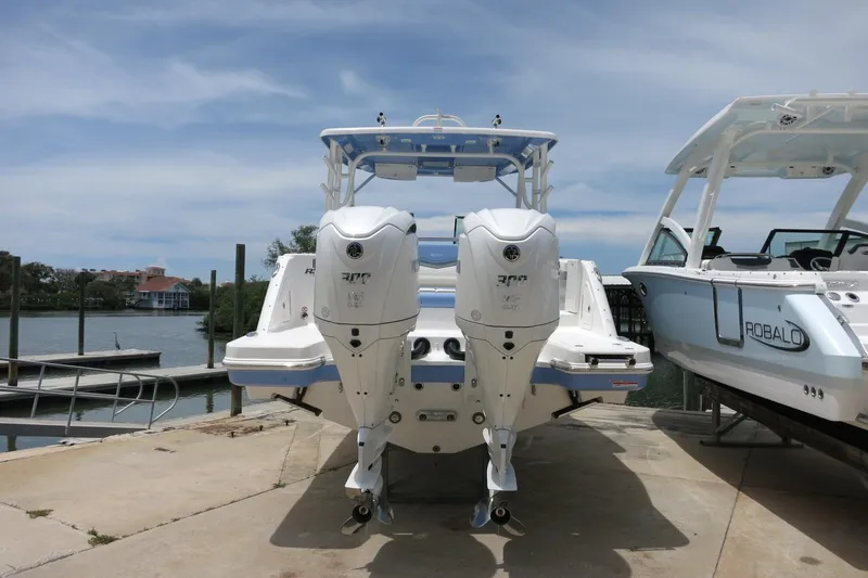 Slide: The Image of 2025 Robalo R317 Dual Console boat with twin engines docked by the water. - 9