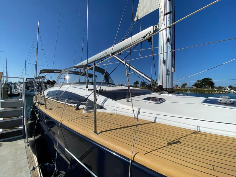 Slide: The Image of 2013 Jeanneau 57 sailboat docked, showcasing sleek design and wooden deck. - 15