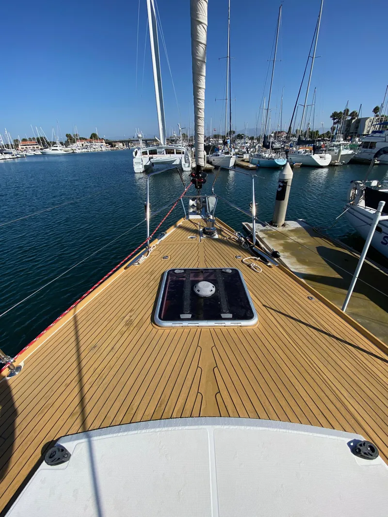 Slide: The Image of 2013 Jeanneau 57 sailboat docked in marina, clear blue sky, wooden deck. - 20