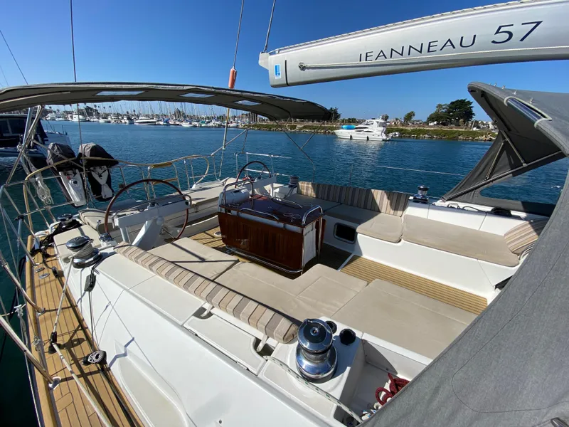 Slide: The Image of 2013 Jeanneau 57 sailboat with spacious deck and seating, docked in a marina. - 33