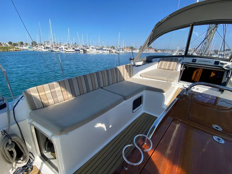 Slide: The Image of 2013 Jeanneau 57 yacht cockpit with striped seating, docked in a marina. - 49