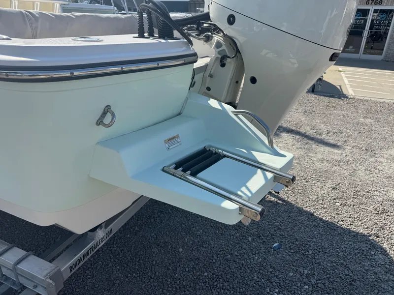 Slide: The Image of 2020 Sundance 20DX boat with swim platform and ladder, parked on gravel. - 3