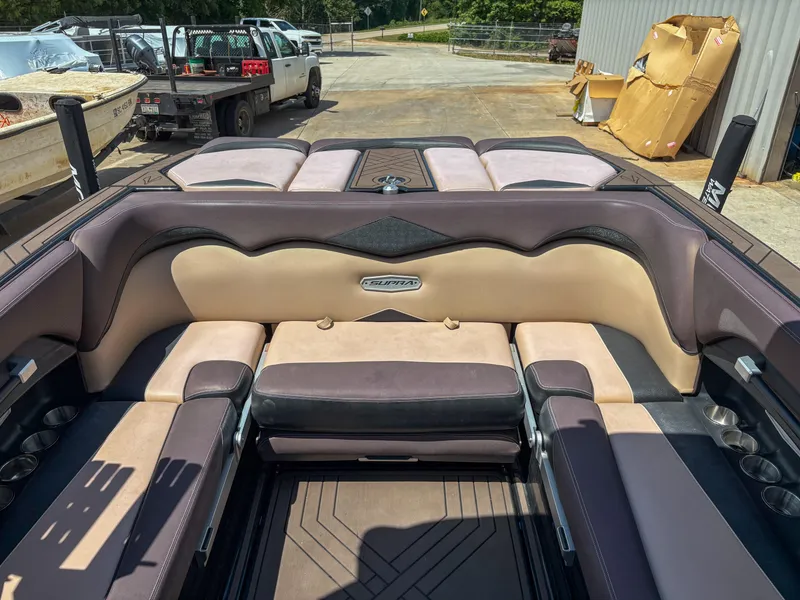 Slide: The Image of 2018 Supra SE 450 boat interior with beige and brown seating, parked outdoors. - 14