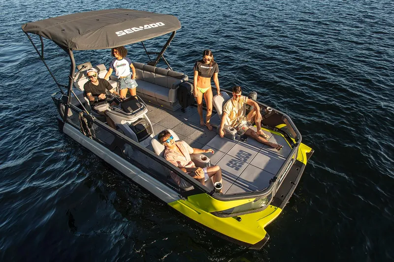 Slide: The Image of Manufacturer Provided Image: 2023 Sea-Doo Switch Sport 21 pontoon boat with passengers enjoying a sunny day on the water. - 2