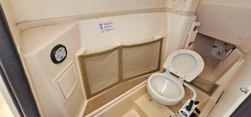 Slide: The Image of Interior of a 2011 Grady-White Freedom 275 boat featuring a compact marine toilet. - 13