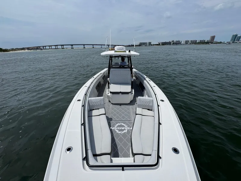 Slide: The Image of 2021 Fountain 38TE boat cruising on water with bridge and cityscape in background. - 24