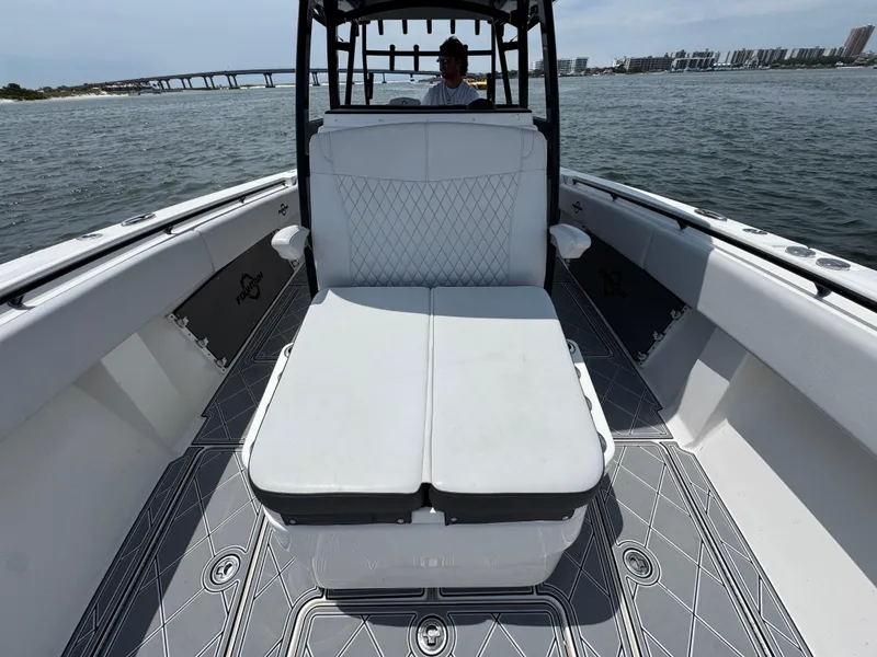 Slide: The Image of 2021 Fountain 38TE boat interior with white seating, on water, bridge in background. - 26