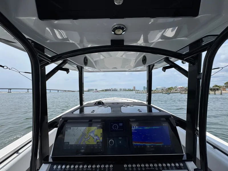 Slide: The Image of 2021 Fountain 38TE boat cockpit with navigation screens, overlooking a scenic waterfront view. - 35