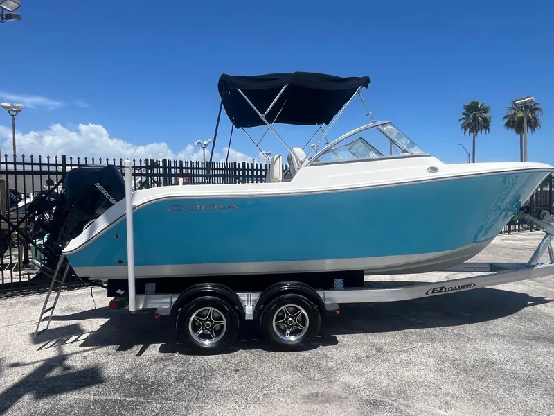 The Image of 2022 Cobia 220 Dual Console boat on trailer under clear blue sky. - 0