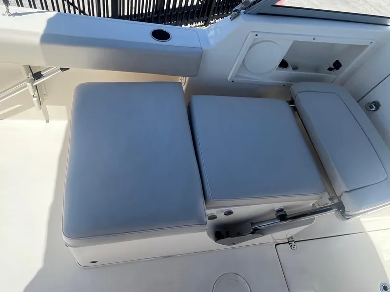 Slide: The Image of 2022 Cobia 220 Dual Console boat seating area with cushioned seats and storage compartment. - 11
