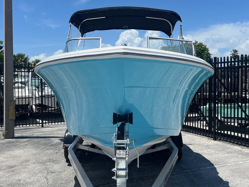 Slide: The Image of 2022 Cobia 220 Dual Console boat on EZ Loader trailer, blue hull, sunny day. - 2