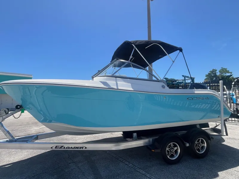 Slide: The Image of 2022 Cobia 220 Dual Console boat on trailer, blue hull, sunny day. - 3