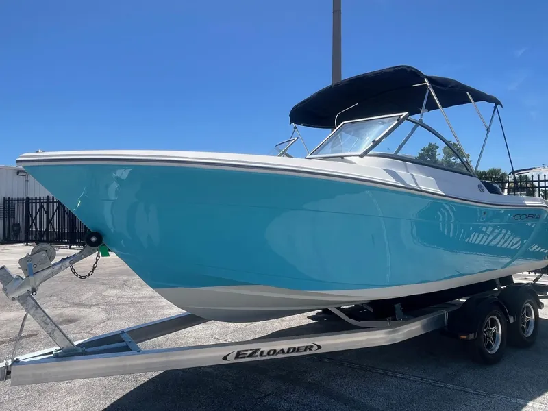 Slide: The Image of 2022 Cobia 220 Dual Console boat on trailer, blue hull, sunny day. - 4