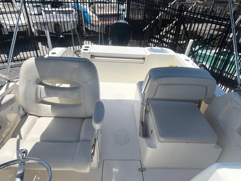 Slide: The Image of 2022 Cobia 220 Dual Console boat interior with white seating and steering wheel. - 7
