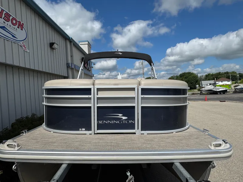 Slide: The Image of 2019 Bennington SX 21 SSRCX pontoon boat at a dealership under a blue sky. - 2