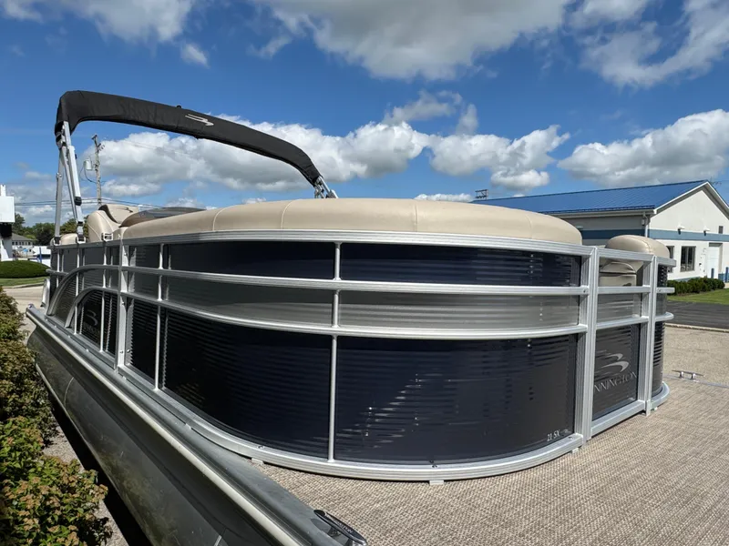 Slide: The Image of 2019 Bennington SX 21 SSRCX pontoon boat with canopy, parked outdoors under blue sky. - 6