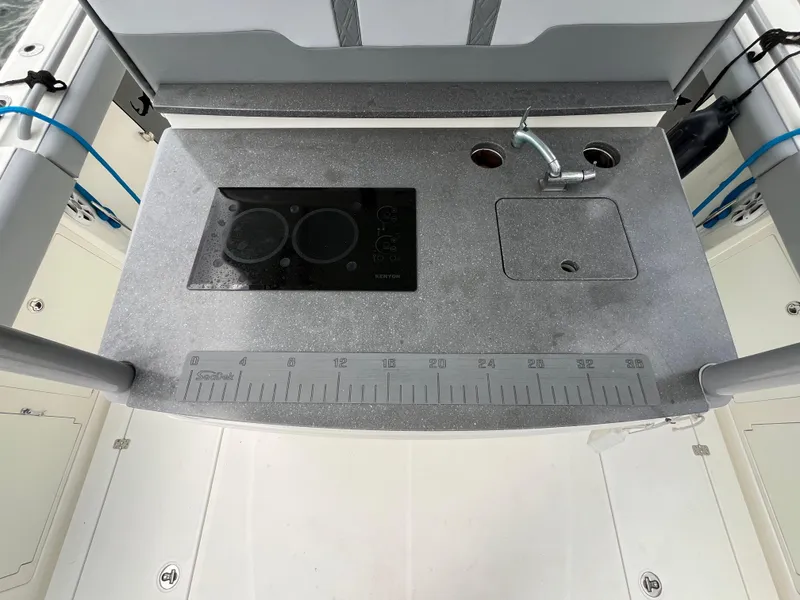 Slide: The Image of 2017 Mako 414 CC Bluewater boat kitchen with sink, stove, and measuring ruler. - 36