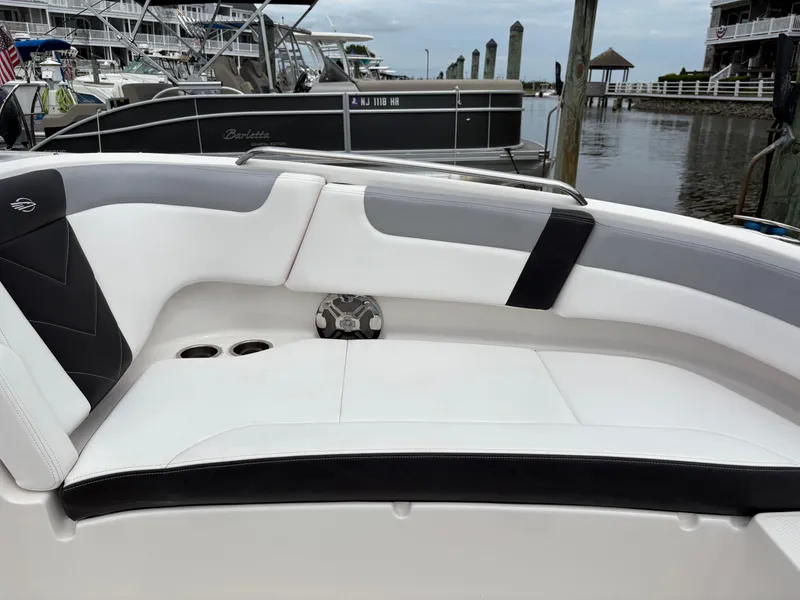 Slide: The Image of 2020 Chaparral 250 Suncoast boat interior with white and black seating at a marina. - 26