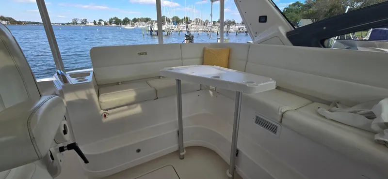 Slide: The Image of 2004 Tiara Yachts 5200 Sovran interior with white seating and table, overlooking marina. - 5