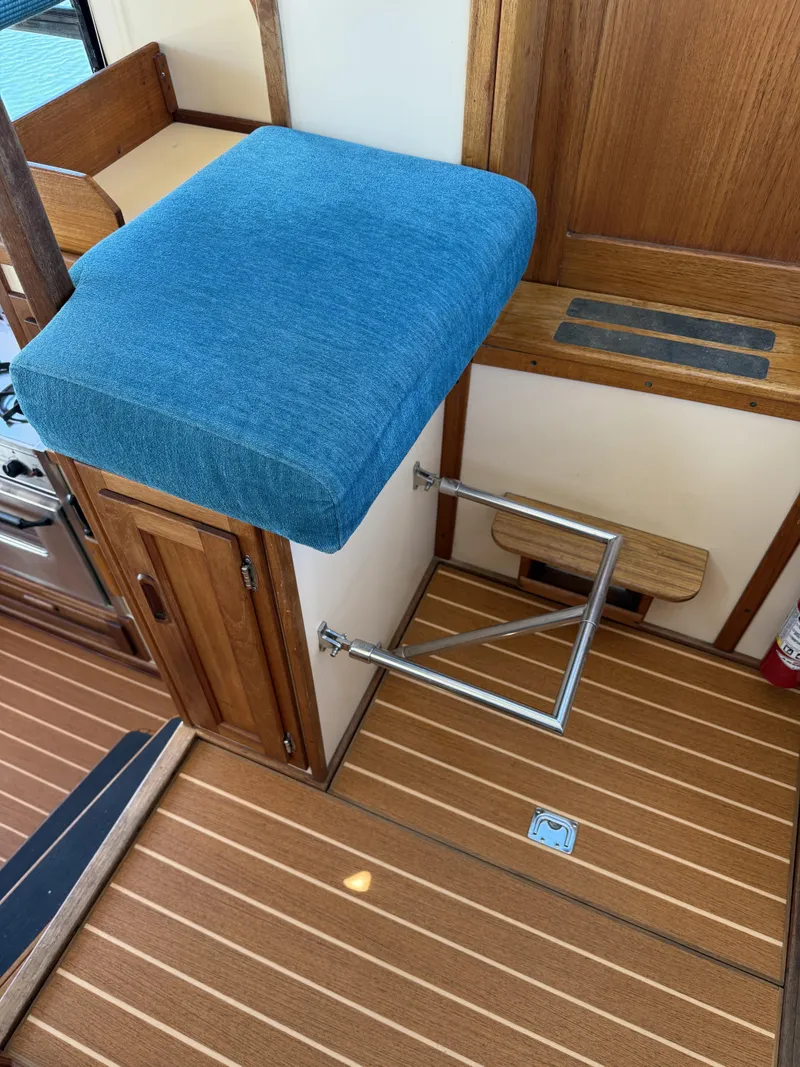 Slide: The Image of Interior of a 1997 Nordic Tug 26 with blue cushioned seat and wooden flooring. - 11