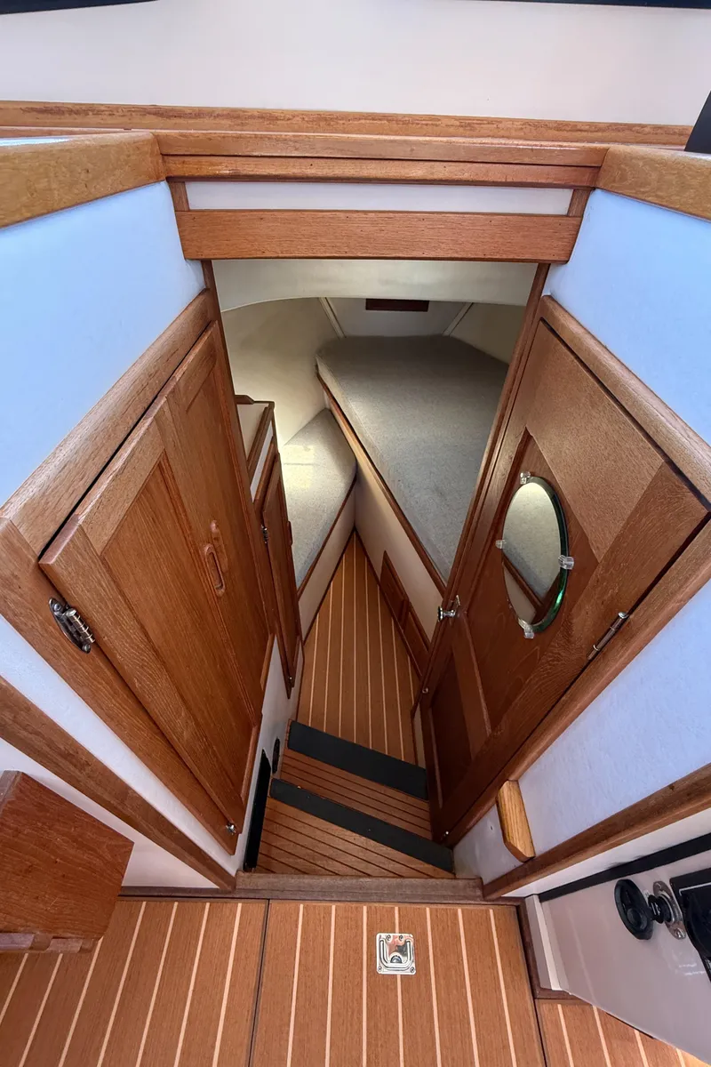 Slide: The Image of Interior view of 1997 Nordic Tug 26, featuring wooden cabinetry and cozy sleeping area. - 13