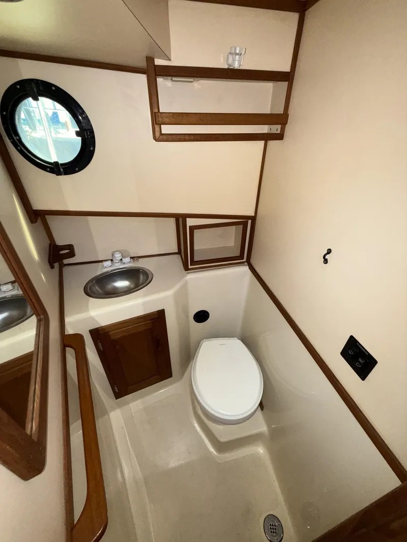 Slide: The Image of 1997 Nordic Tug 26 bathroom with sink, toilet, and porthole window. - 15