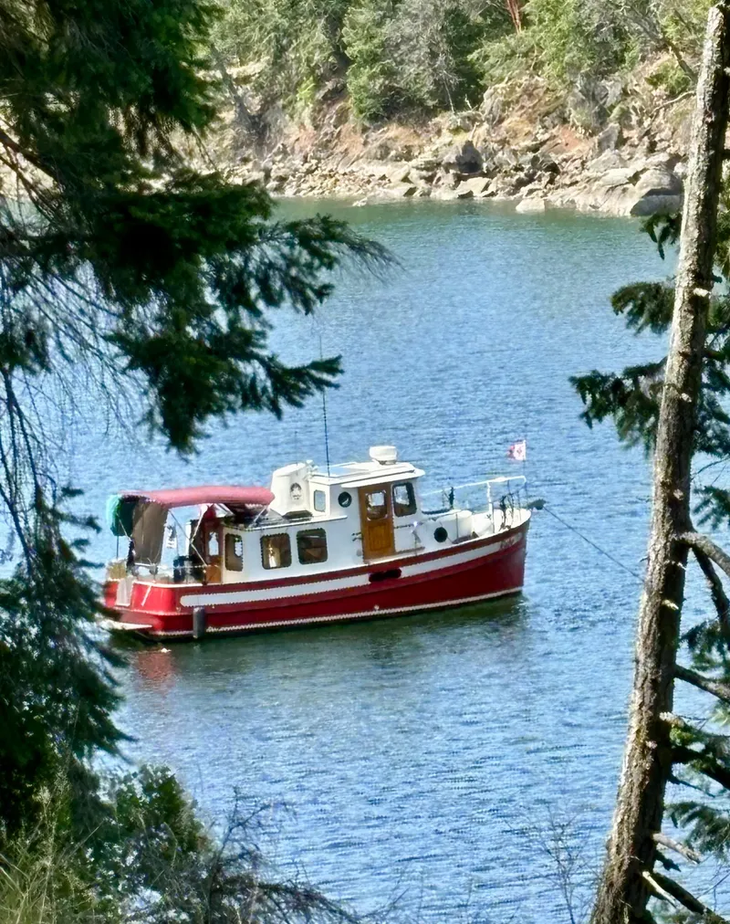Slide: The Image of Red 1997 Nordic Tug 26 boat anchored in a serene forested lake. - 21