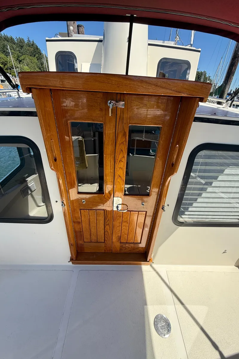 Slide: The Image of Wooden cabin door on a 1997 Nordic Tug 26 boat, docked in a marina. - 5