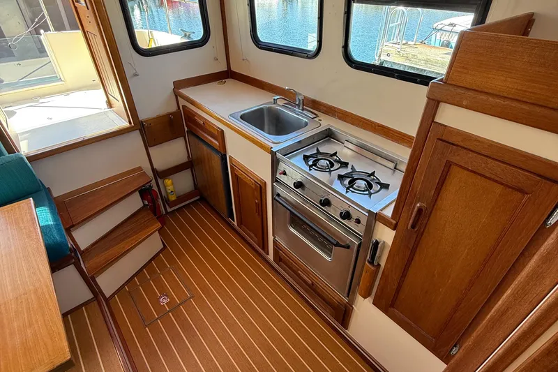 Slide: The Image of 1997 Nordic Tug 26 interior kitchen with stove, sink, and wooden cabinetry. - 6