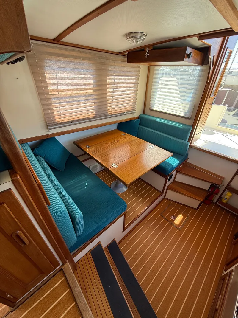 Slide: The Image of Cozy interior of 1997 Nordic Tug 26 with wooden table and teal seating. - 7