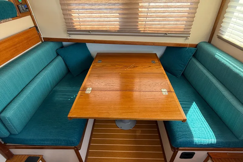 Slide: The Image of Cozy dining area in a 1997 Nordic Tug 26 with teal cushions and wooden table. - 8