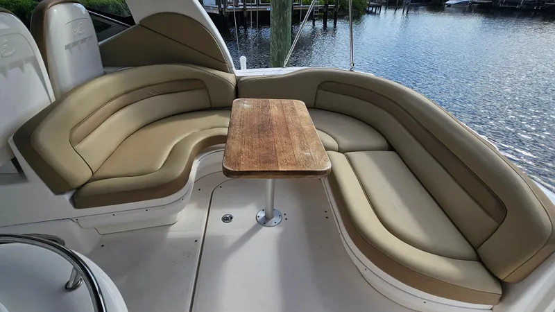 Slide: The Image of 2007 Sea Ray 340 Sundancer boat interior with curved seating and wooden table by the water. - 20