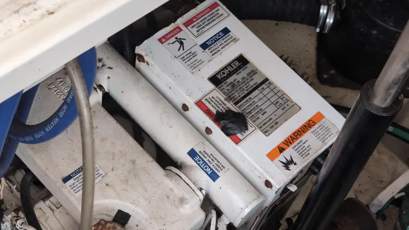 Slide: The Image of Engine compartment of 2007 Sea Ray 340 Sundancer with Kohler generator and warning labels. - 49