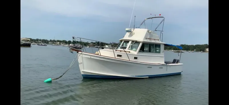 Slide: The Image of 1986 Cape Dory 26 Fly boat anchored on calm water, clear sky background. - 2