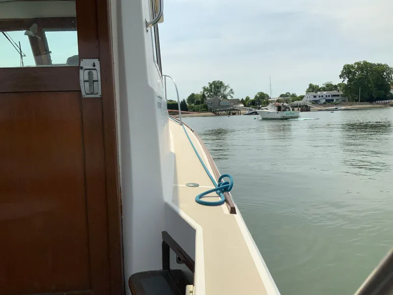 Slide: The Image of 1986 Cape Dory 26 Fly on calm water near shoreline with houses in background. - 6