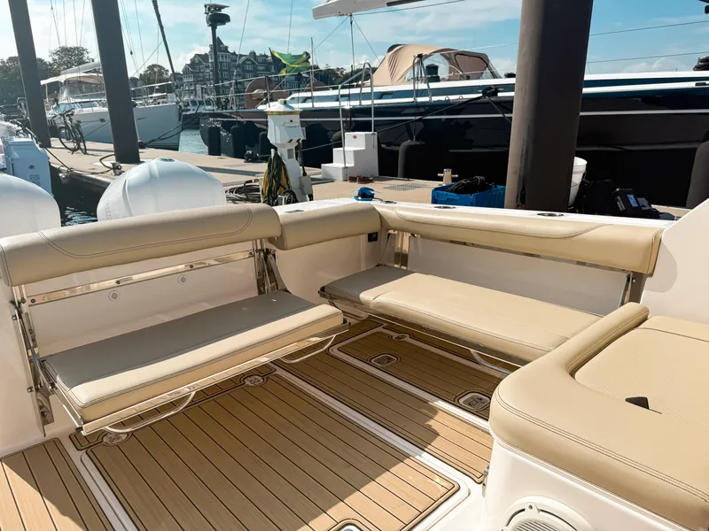 Slide: The Image of 2018 Pursuit DC 325 Dual Console boat interior with beige seating and wooden deck. - 13