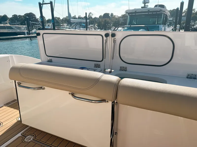 Slide: The Image of 2018 Pursuit DC 325 Dual Console boat interior with seating and marina view. - 16