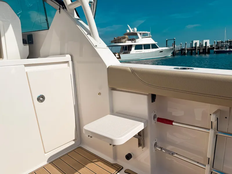 Slide: The Image of 2018 Pursuit DC 325 Dual Console boat interior with docked yacht in background. - 19