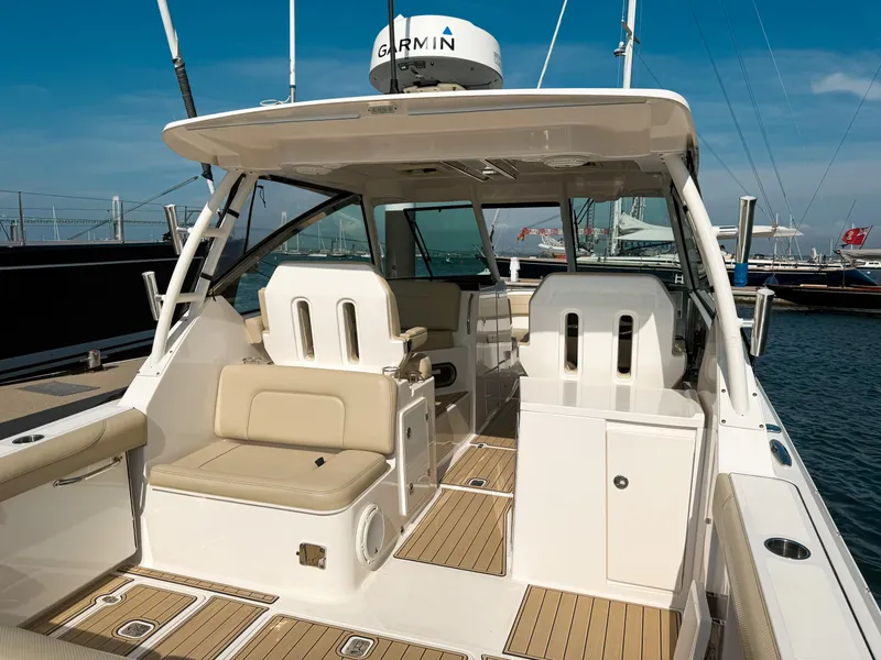 Slide: The Image of 2018 Pursuit DC 325 Dual Console boat interior with beige seating and Garmin equipment. - 22